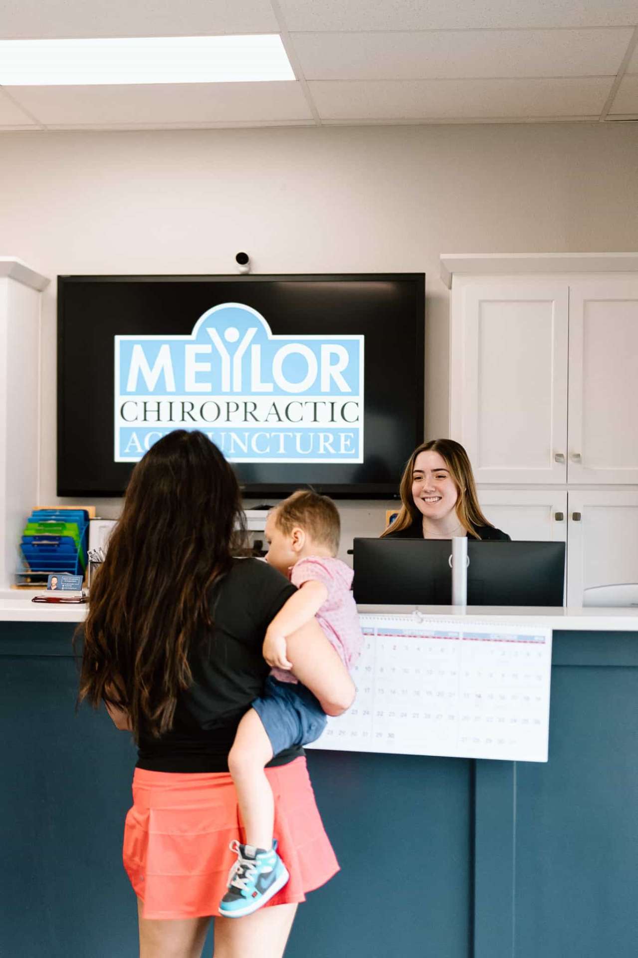 Family at chiropractic reception with mother holding child